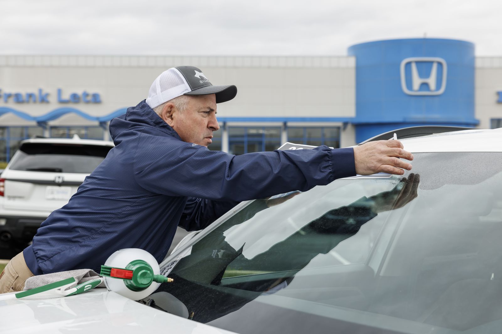 Pep setting a banner across a windshield at Frank Leta Honda