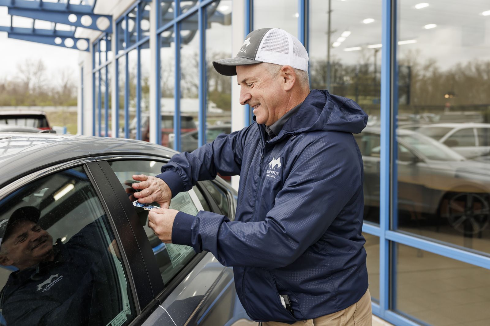 Pep pressing a QR placard onto a car's door glass at Frank Leta Honda