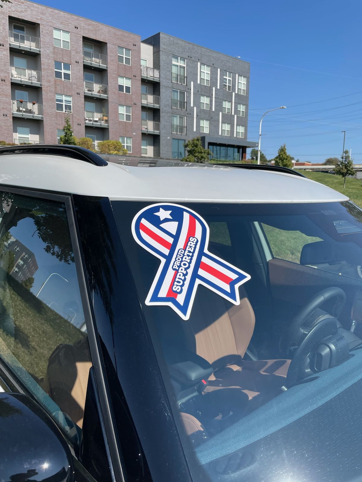 A Proud Supporters ribbon on a windshield